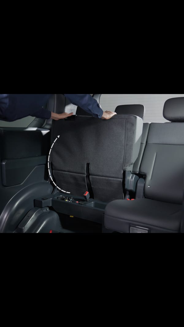 60:40-Klappsitz im Fond des Kia PV5 WAV, hochgeklappt, um Platz für einen Rollstuhl zu schaffen – der danebenliegende Sitz bleibt für eine Begleitperson verfügbar.